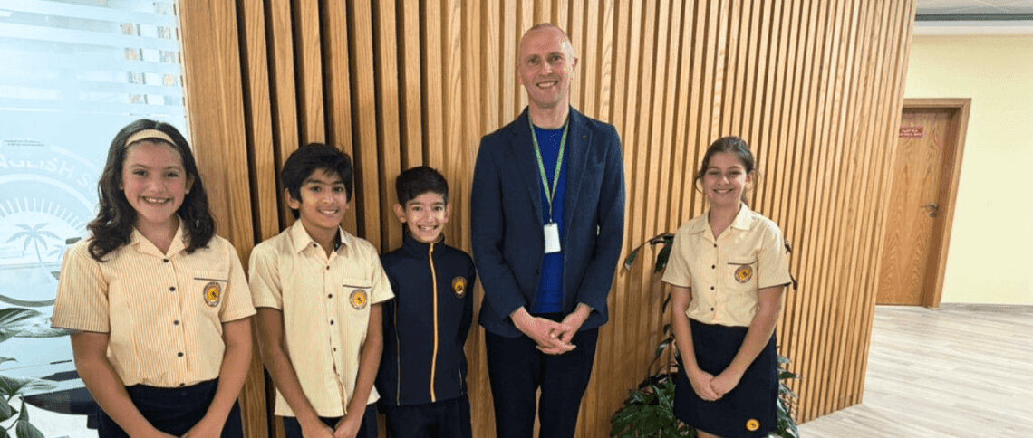 Four students and Simon Camby stand smiling at Horizon English School, Dubai